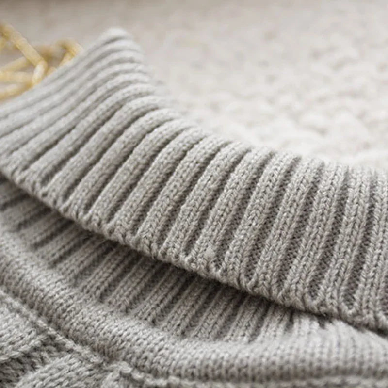 A close-up view of the ribbed turtleneck collar on a grey cable-knit sweater.