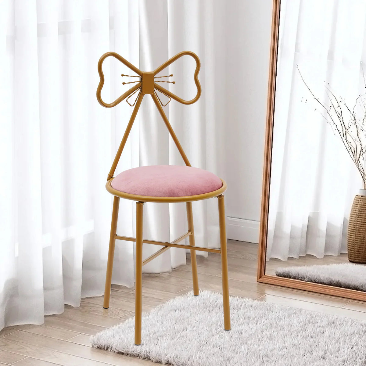 A pink velvet vanity chair with gold frame and a butterfly backrest, placed on a white rug.