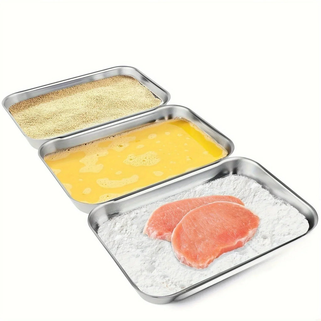 Three stainless steel trays used for breading food with flour, egg wash, and breadcrumbs