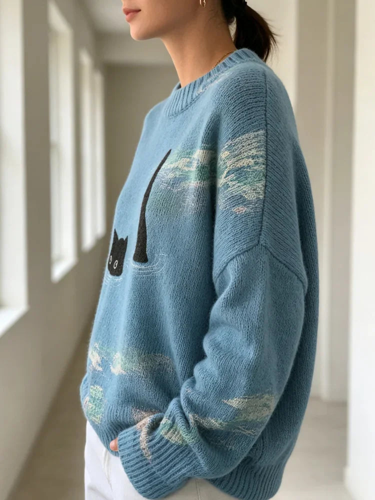 Side profile view of a woman wearing a blue knitted sweater with a black cat graphic