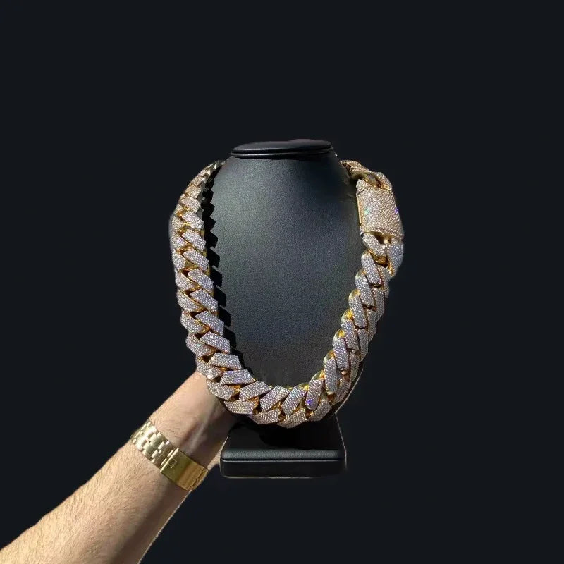 Iced out gold tone Cuban link necklace on a jewelry display stand held by a hand