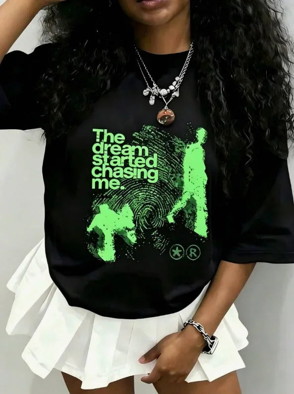 Model wearing black t-shirt with green graphic print, paired with a white skirt