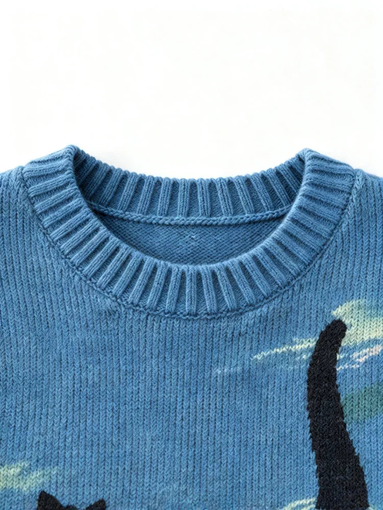 Close-up detail of the ribbed crew neck collar on a blue graphic knit sweater