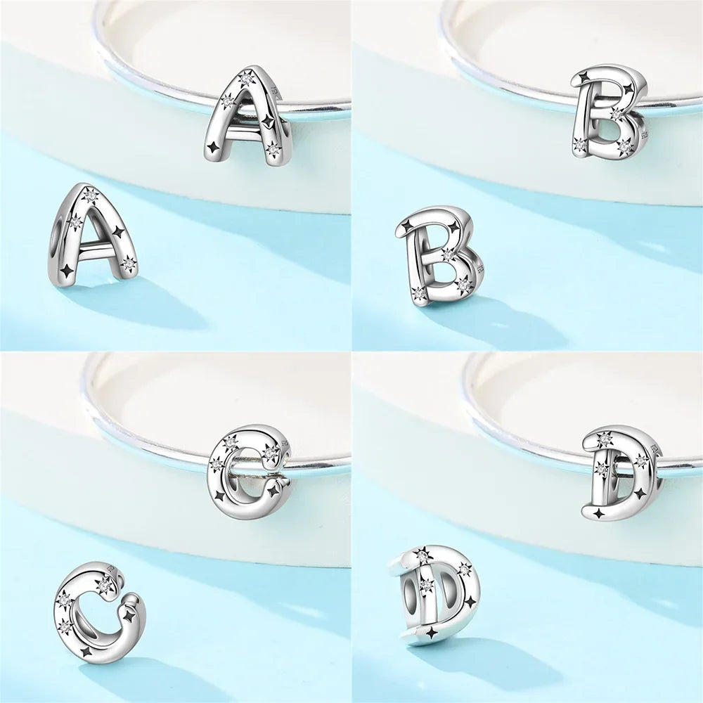 Sterling silver letter charms A, B, C, D featuring star patterns on a pale blue background with a matching bracelet.