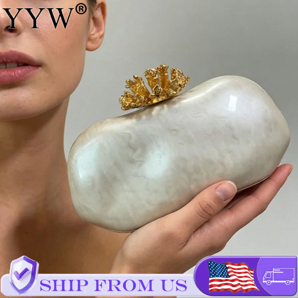 White marbled acrylic evening clutch with gold coral-shaped clasp held by a woman