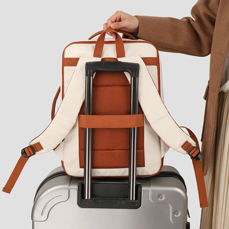 Back of a beige backpack attached to a suitcase handle