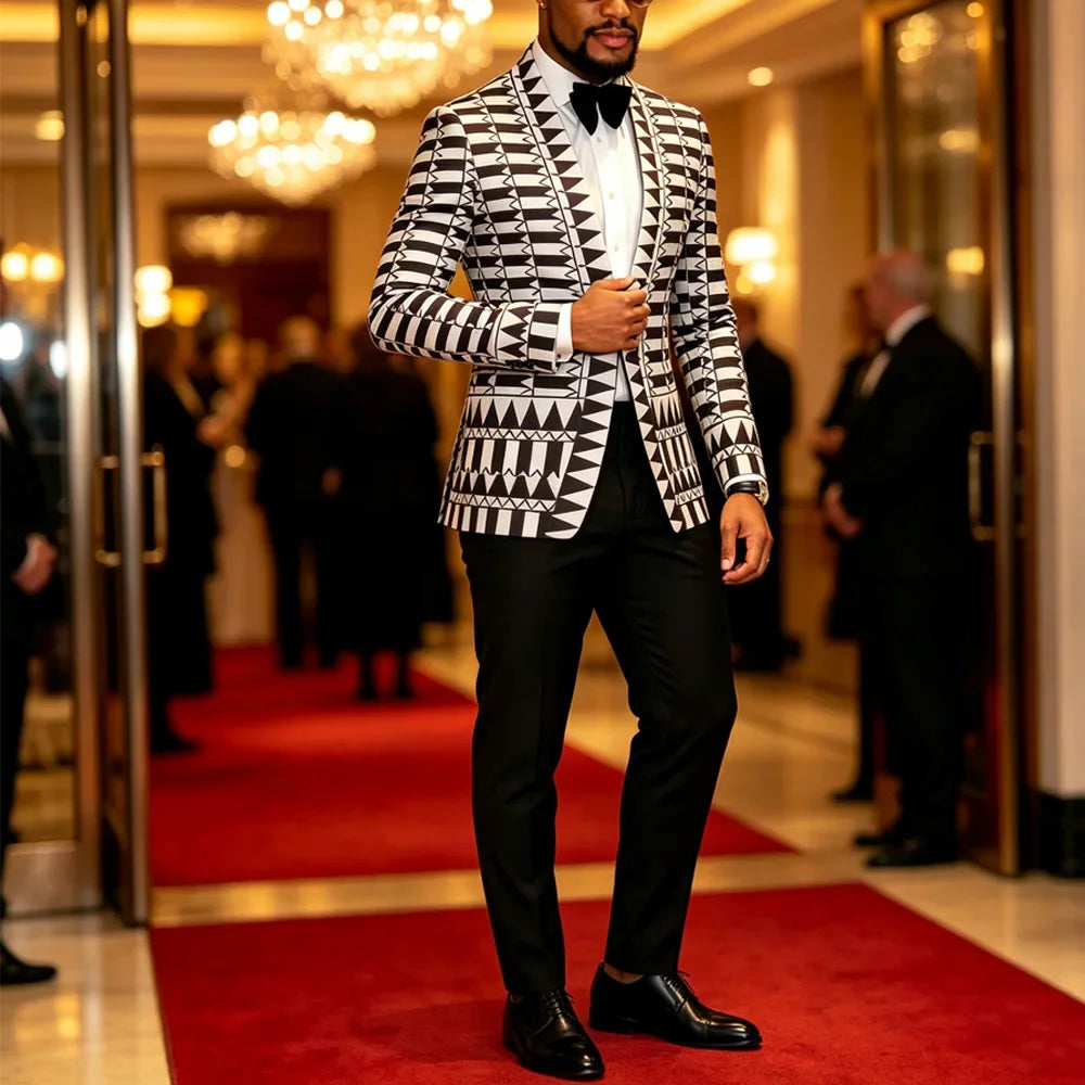 A man wearing a black and white geometric print blazer with a black shawl lapel and black trousers.