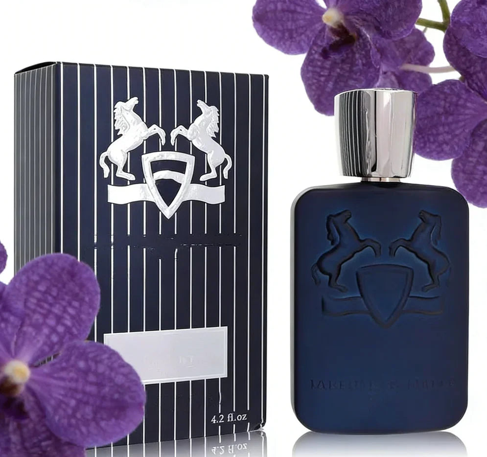 Dark blue perfume bottle with matching box next to purple orchid flowers
