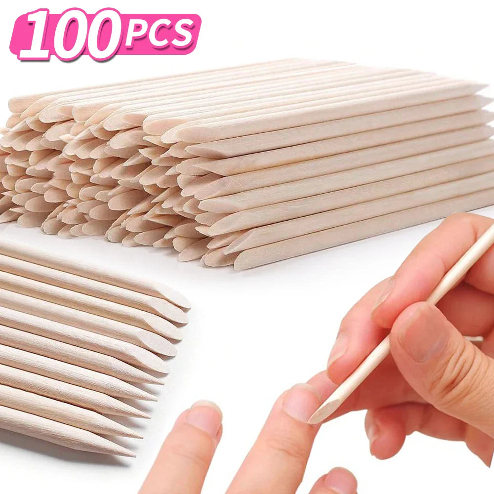 A large pile of orange wood sticks with a hand demonstrating cuticle pushing