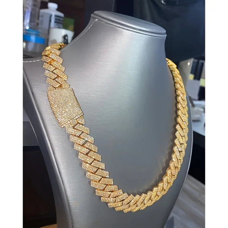 Gold-tone Cuban link chain necklace fully iced out with sparkling stones on a grey display stand.