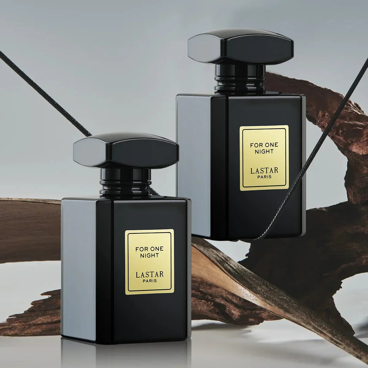 Two black perfume bottles positioned in front of abstract wooden decor on a gray background.