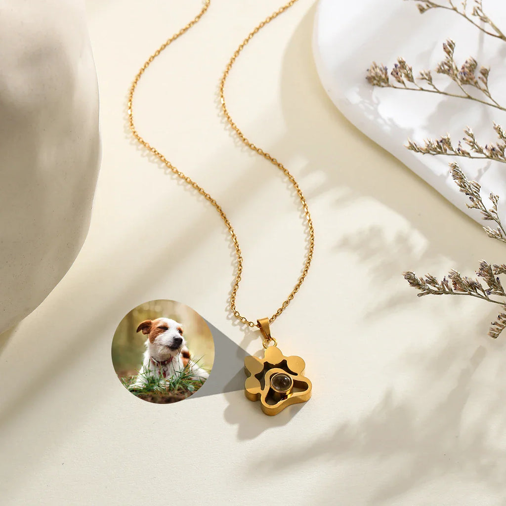 Gold paw-shaped projection necklace showing a dog photo being projected.