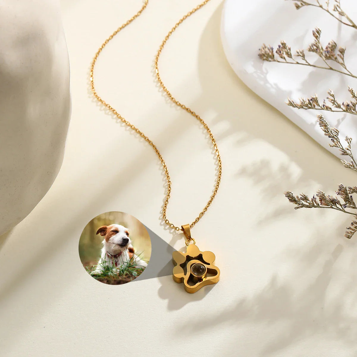 Gold paw-shaped projection necklace showing a dog photo being projected.