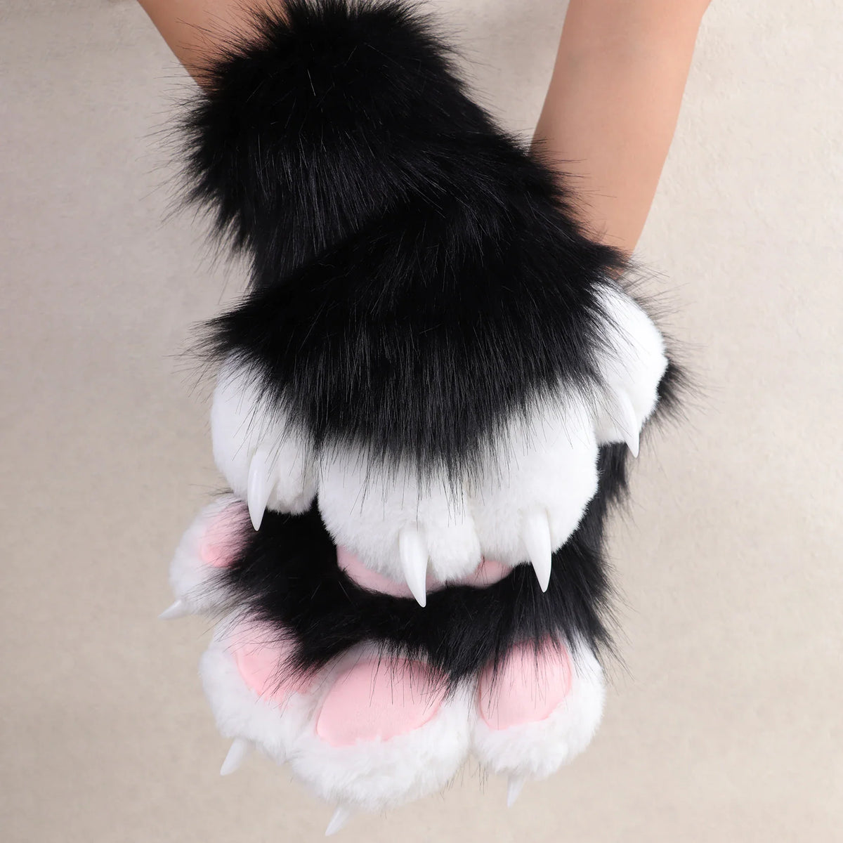 Black and white plush animal paw gloves with pink paw pads and claws.