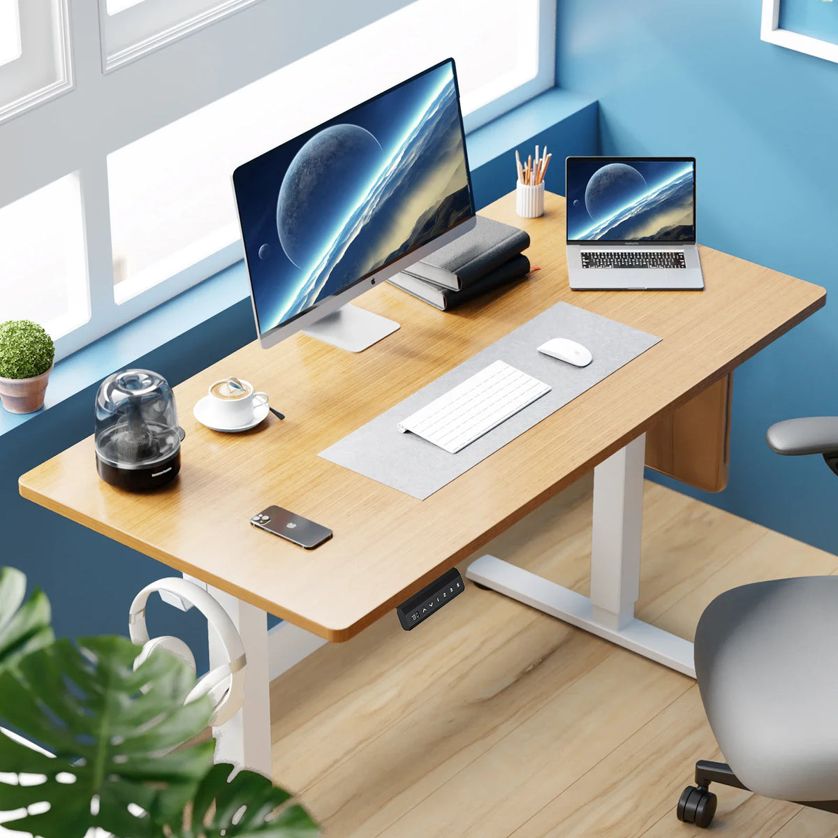 Modern home office setup with wood electric standing desk, monitor, laptop and accessories