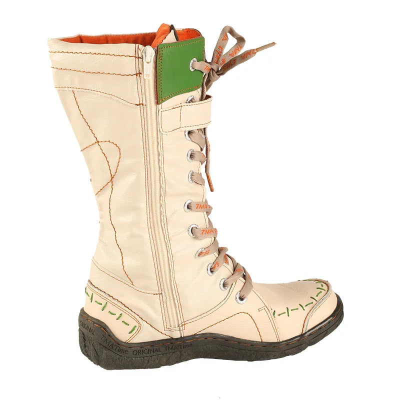 Side profile of beige mid-calf lace-up boots with green stitched details and orange lining