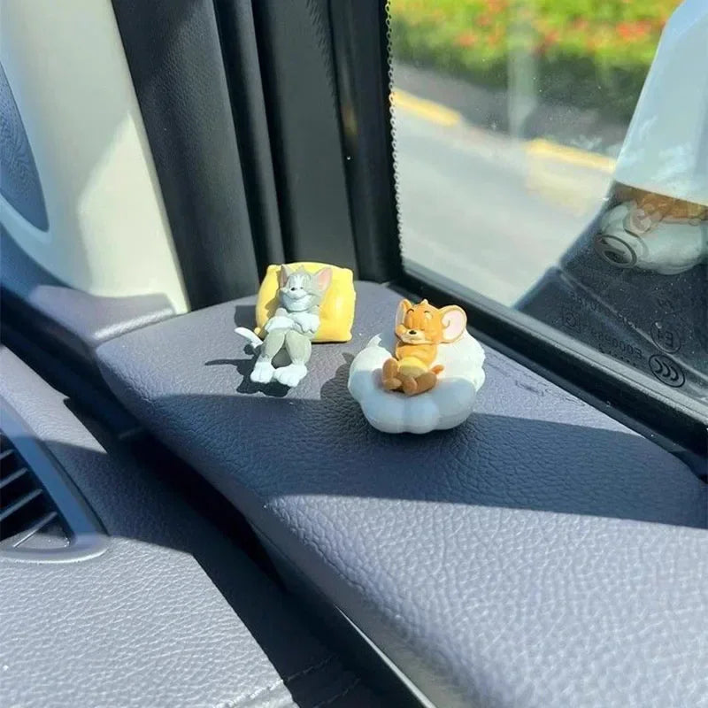 Miniature cat and mouse figurines on a car interior surface