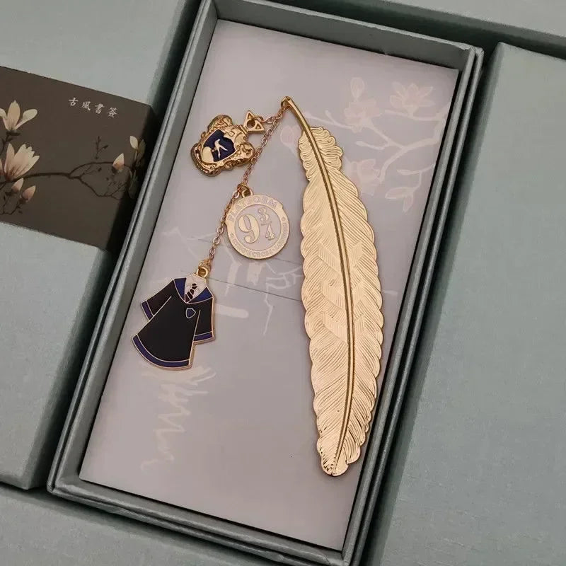 Golden metal feather bookmark with house crest charm and robe pendant in a box