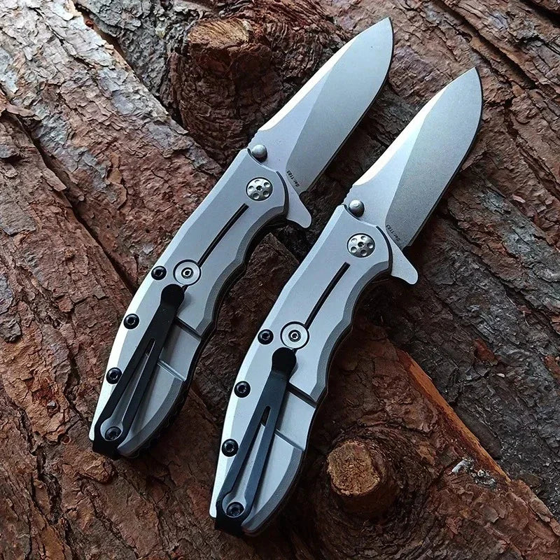 Two folding pocket knives with silver metallic handles and clips on a wooden background