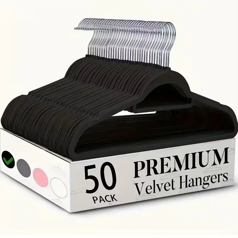 A stack of 50 black velvet hangers with silver hooks in a box.