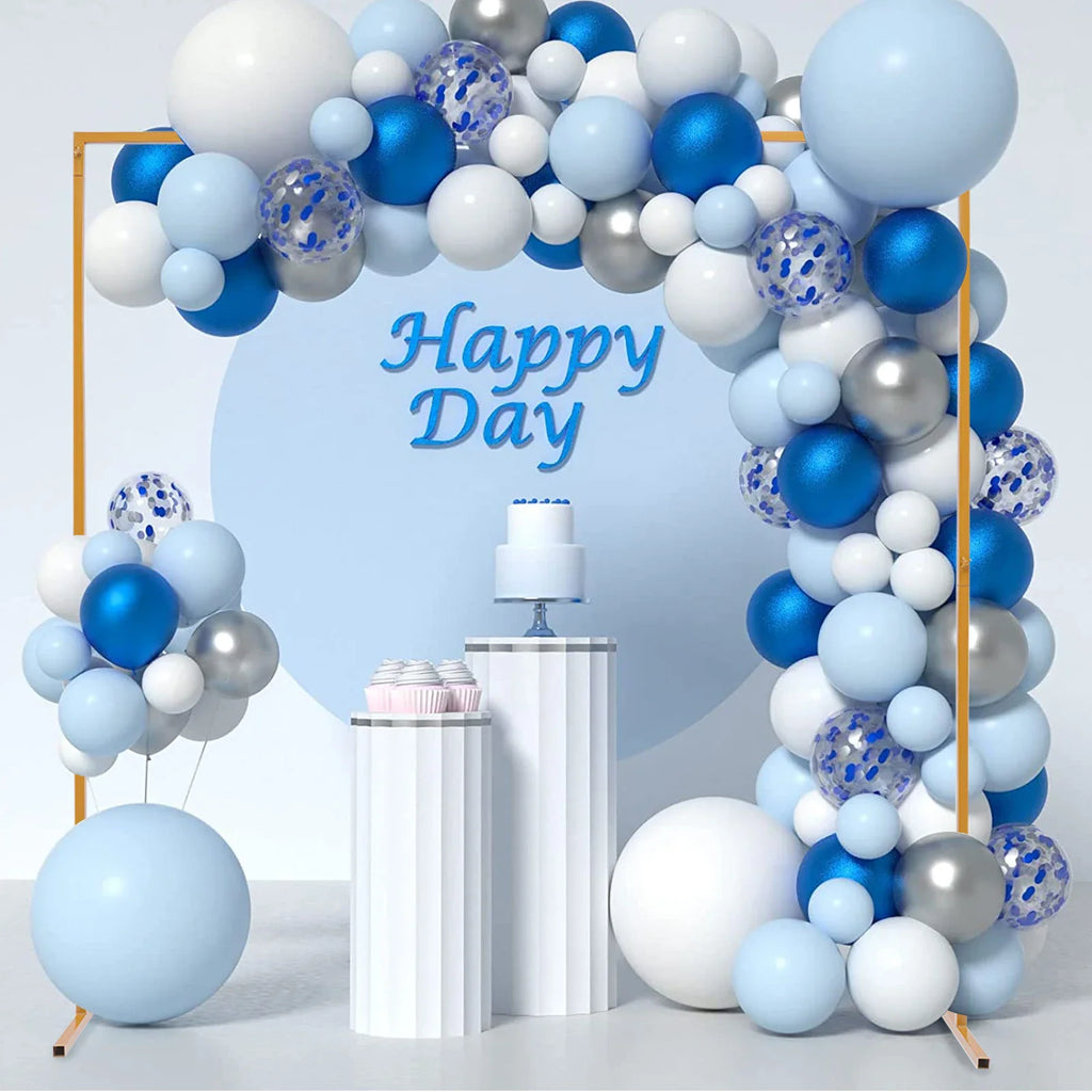 Golden square arch stand with blue and silver balloons and a white cake on pedestals