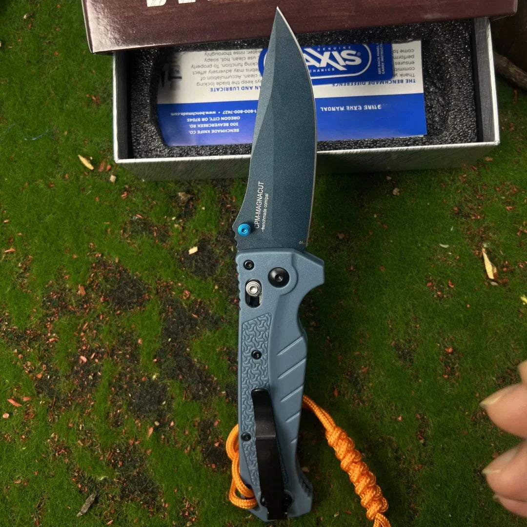 Grey folding pocket knife with a drop point blade and textured handle with an orange paracord lanyard
