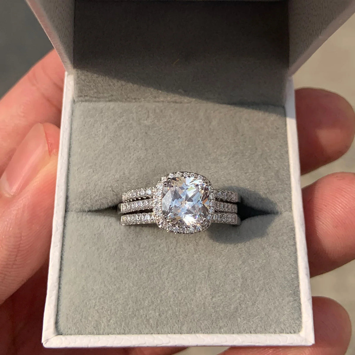 Three-piece cushion cut halo wedding ring set inside a grey velvet jewelry box