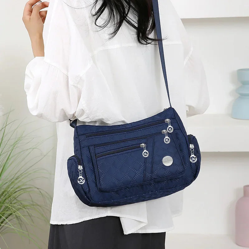 Blue quilted nylon crossbody bag worn by a person