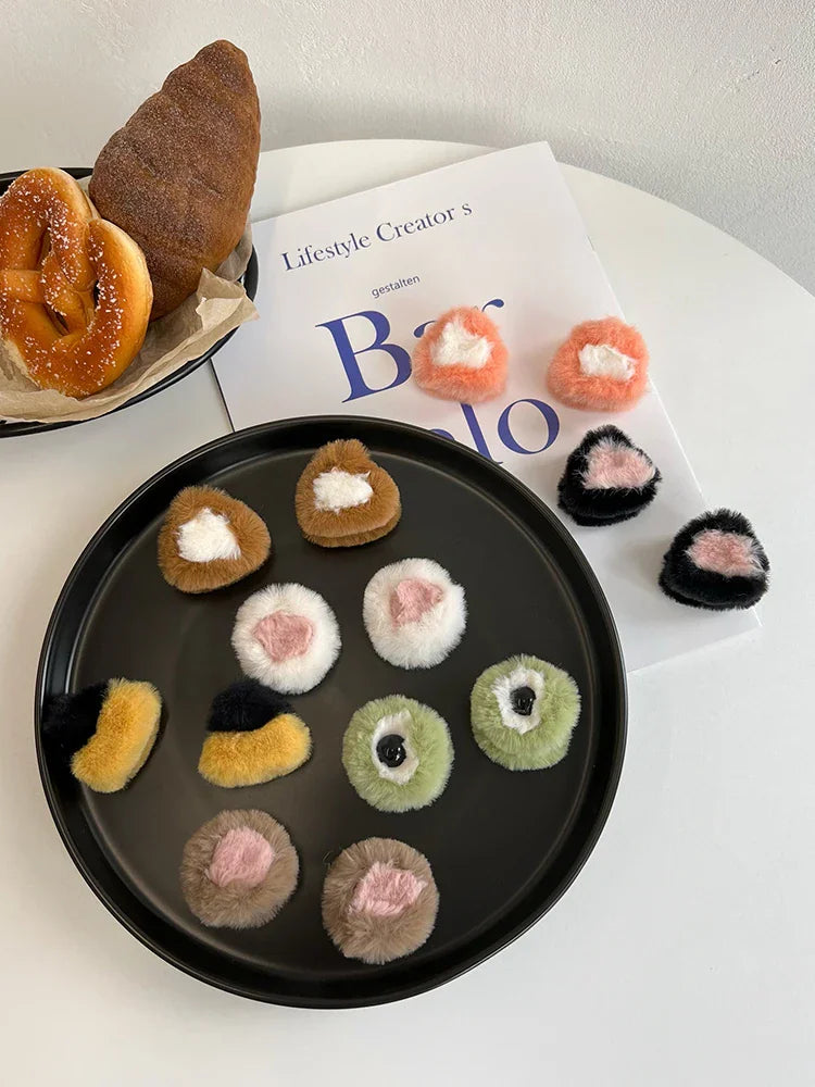 A variety of plush animal ear hair clips arranged on a black plate with bread on the side