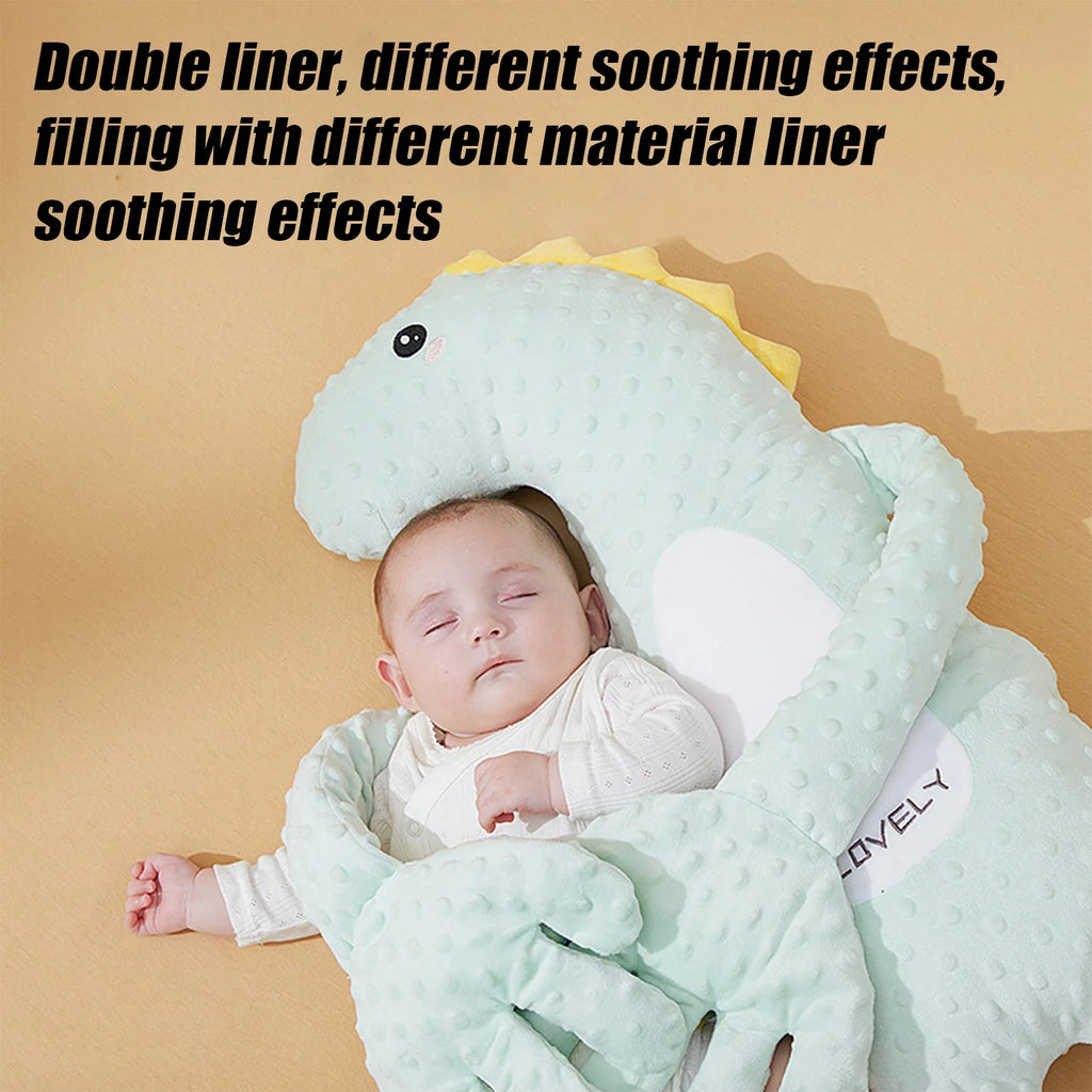 A green dinosaur shaped sleeping pillow next to a baby.