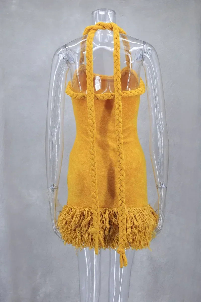 Back view of a mustard yellow velvet halter mini dress with braided straps and fringe hem on a mannequin.