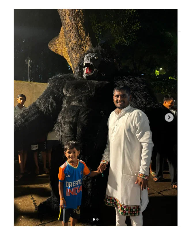 A black king kong mascot costume standing behind a man and a child.