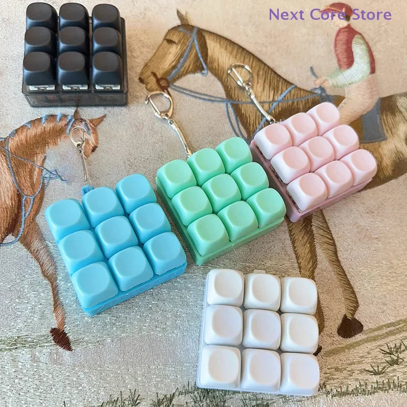 A collection of colorful 9-key keyboard fidget keychains on a patterned background