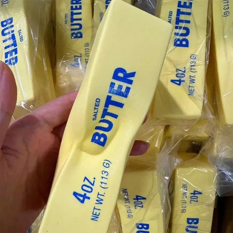 Squishy yellow butter stick fidget toy held in hand with many others in background