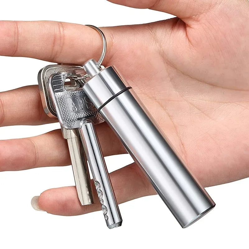 A hand holding a set of stainless steel toothpicks and a metal keychain case with regular house keys.