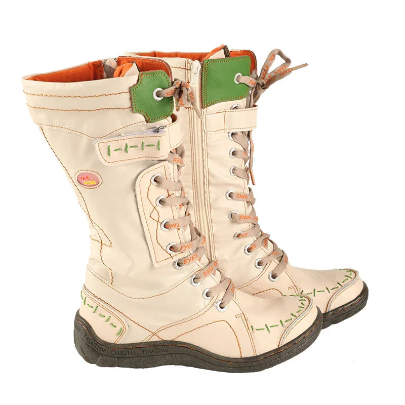 Side view of pair of beige mid-calf lace-up boots with green stitching details