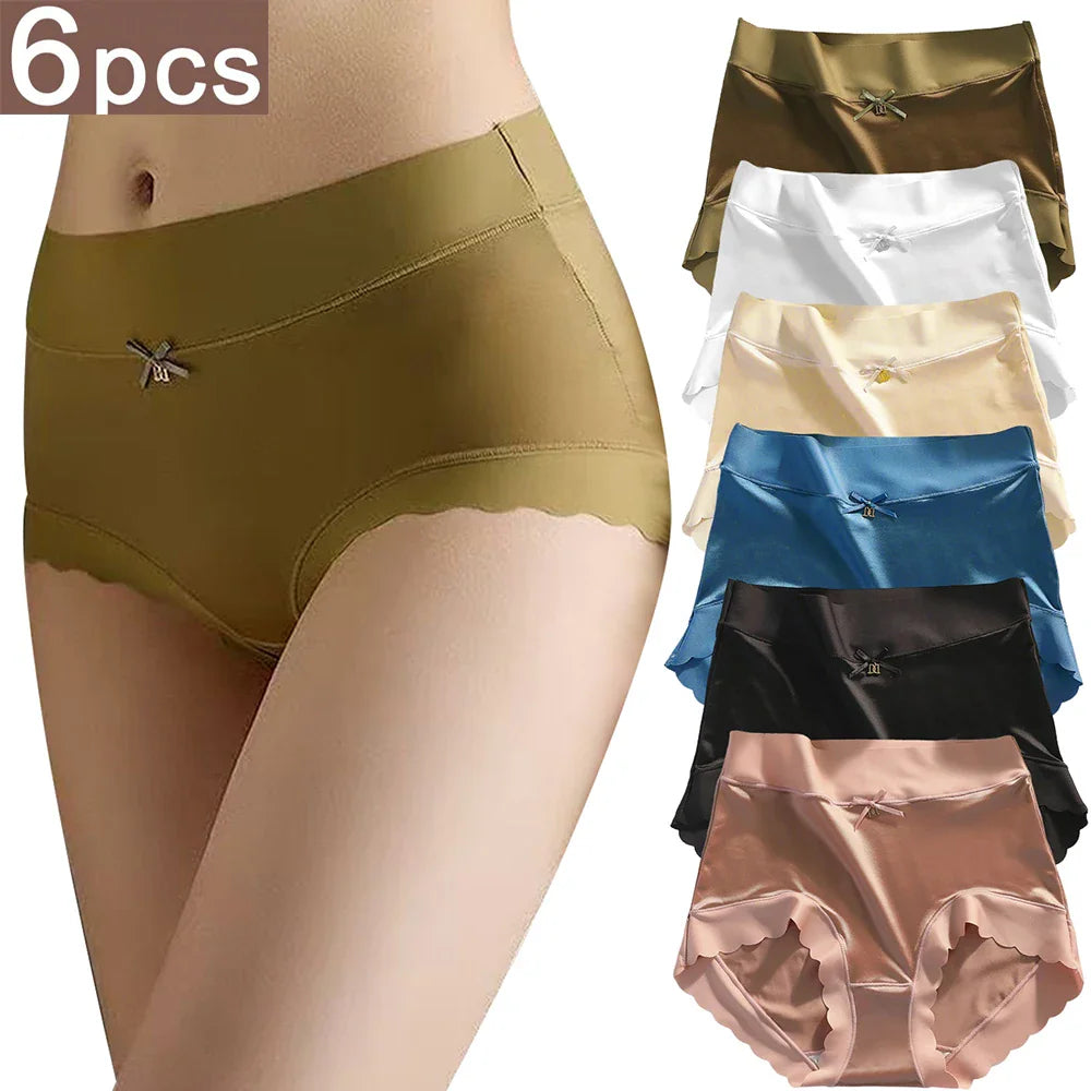 A woman wearing olive green satin panties with a stack of six colorful pairs beside her.