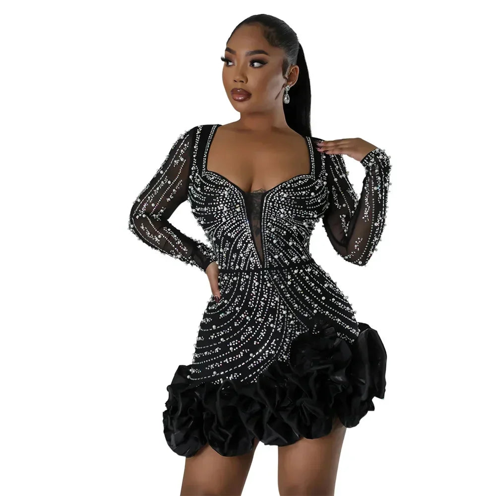 A black long-sleeved mini dress with intricate beadwork and a dramatic ruffled hemline.