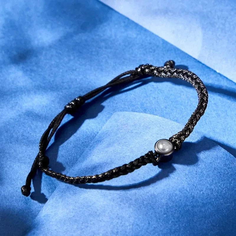 A black braided rope bracelet with a circular center charm.