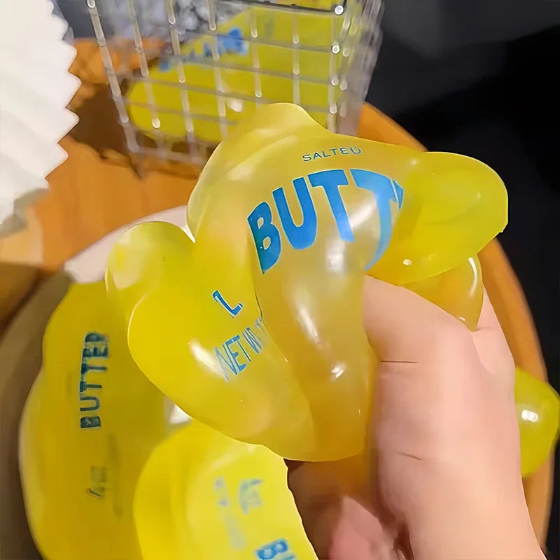 Hand squeezing a yellow butter stick shaped squishy stress relief toy