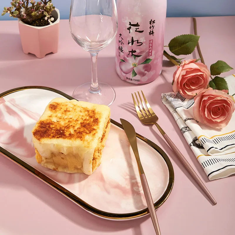 A meal served on a plate with roses and a drink on a pink photography backdrop