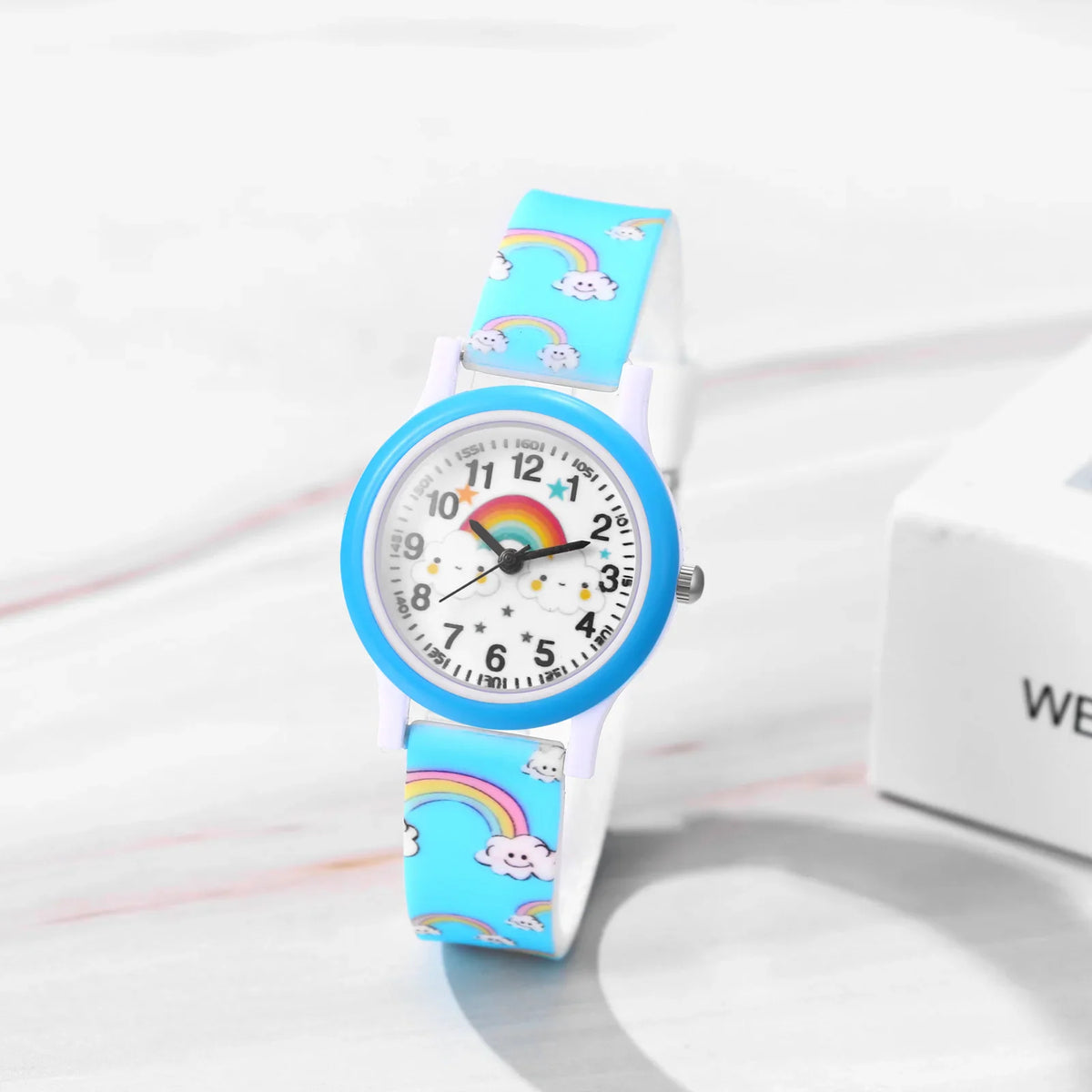 Blue children's watch with rainbow and cloud print on silicone strap, white dial with rainbow graphic