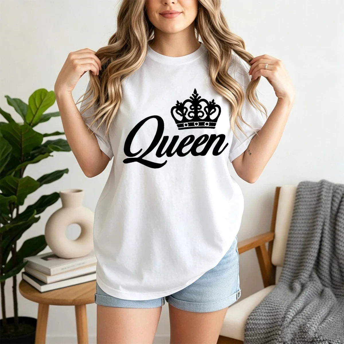 A woman wearing a white short-sleeved t-shirt with a black crown and Queen lettering on the front