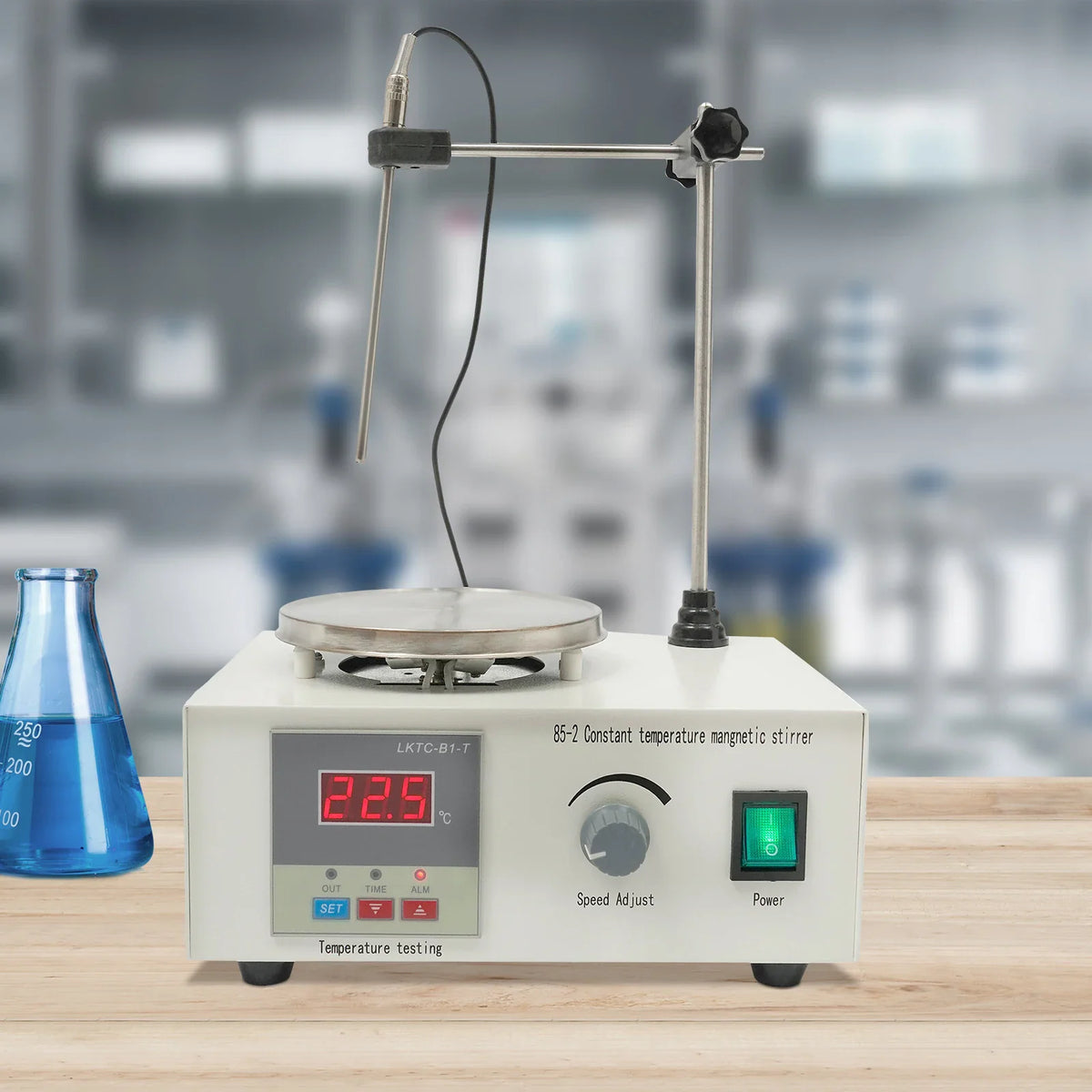 Magnetic stirrer with digital temperature display and heating plate next to a blue liquid flask