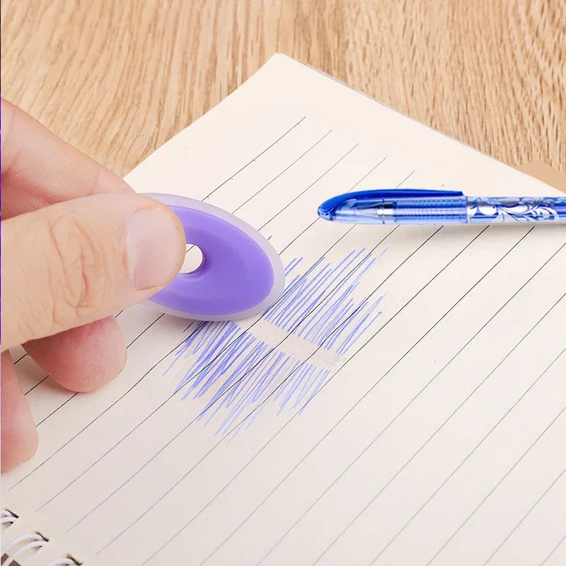 Hand using a circular eraser to remove blue ink marks on notebook paper