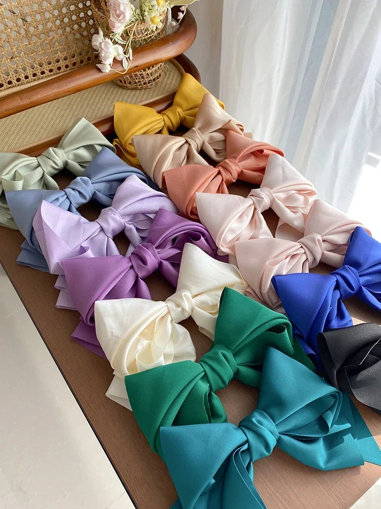A collection of assorted colorful satin bow hair clips arranged on a table