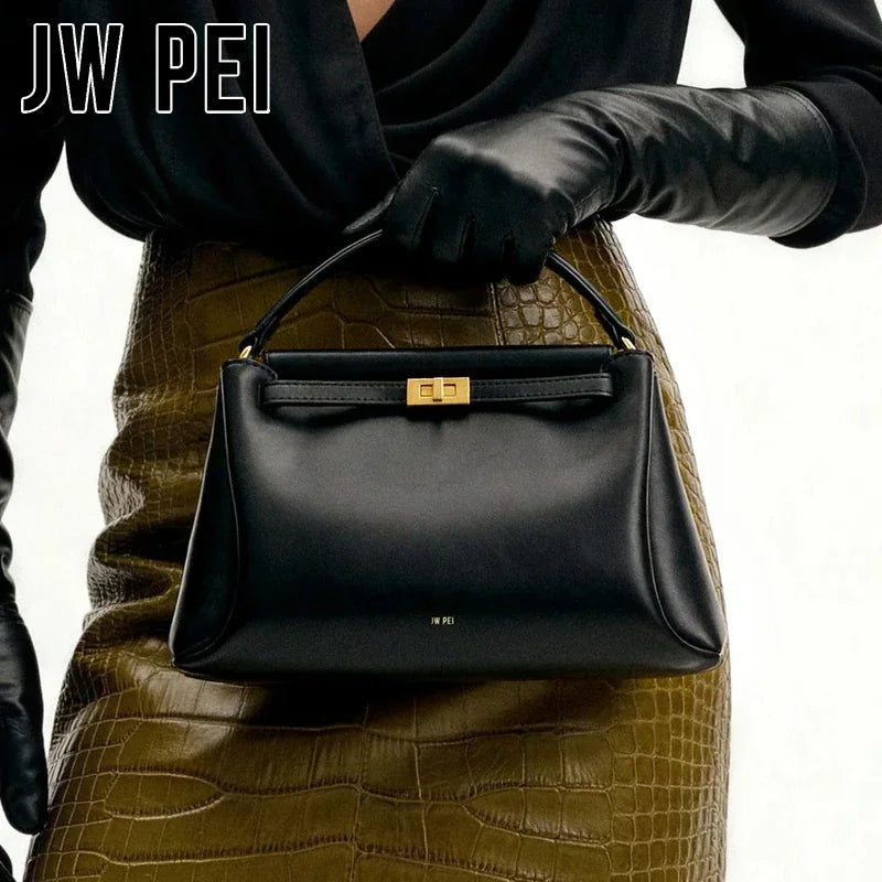 Black mini top handle bag held by a person in a brown crocodile-patterned skirt and black opera gloves