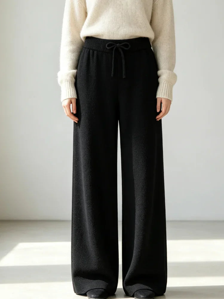 High waisted black knit wide leg pants with a drawstring elastic waist, worn by a woman with a cream sweater