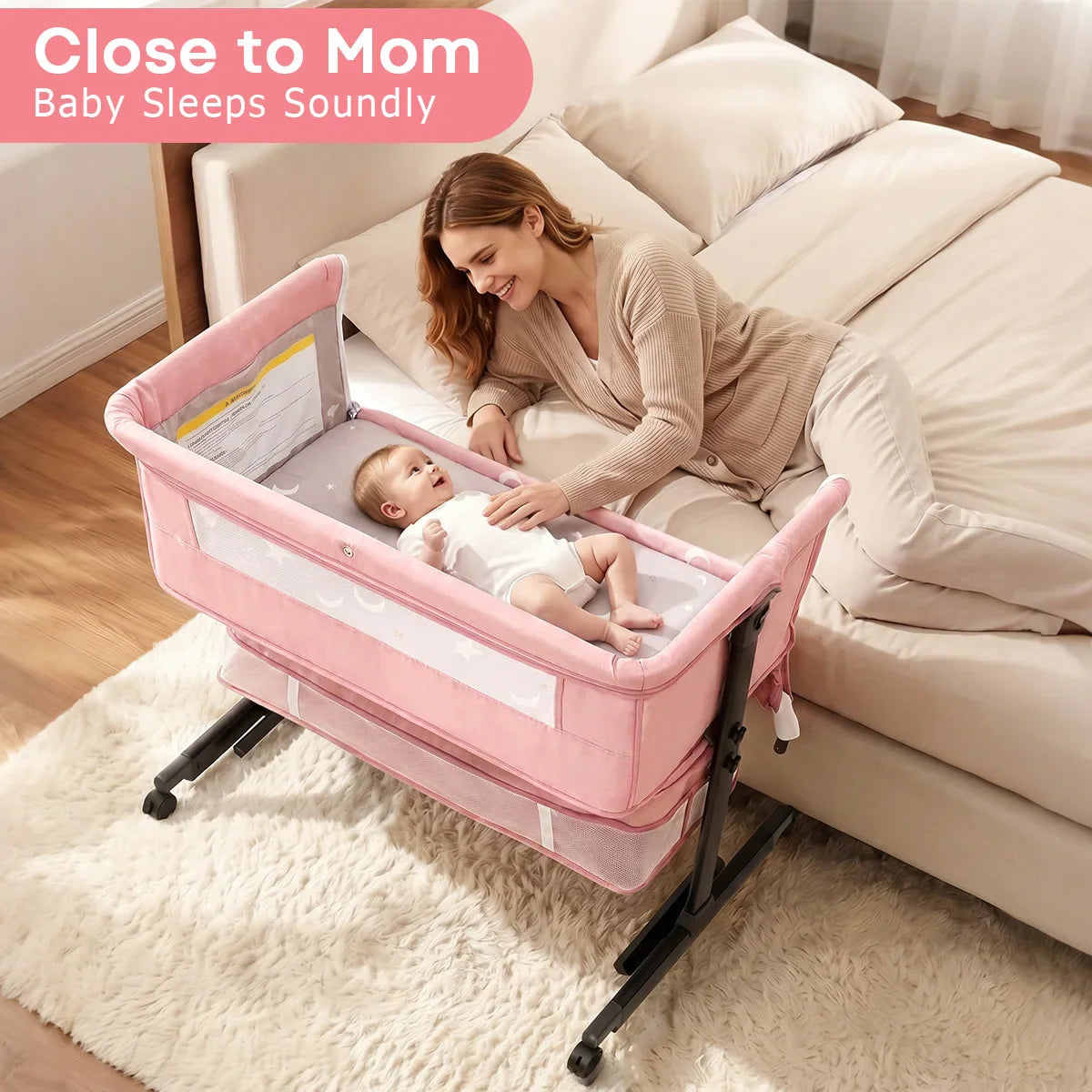 Mother sleeping next to baby in a pink bedside bassinet co-sleeper