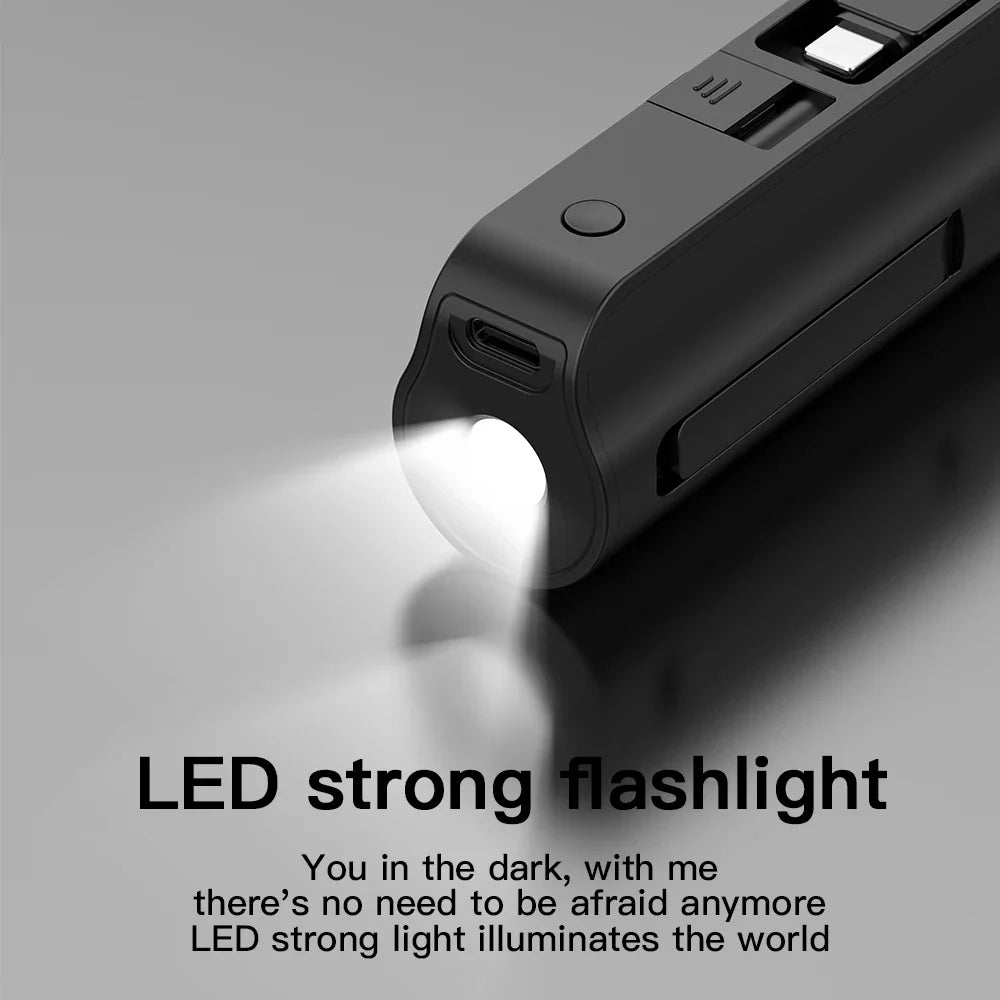 Close up of a black mini portable power bank with an integrated LED flashlight function turned on.